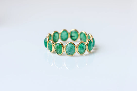 Oval-cut emerald scalloped eternity ring in 18K gold