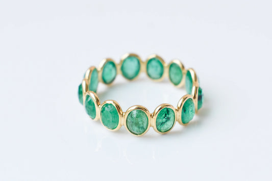 Oval-cut emerald scalloped eternity ring in 18K gold