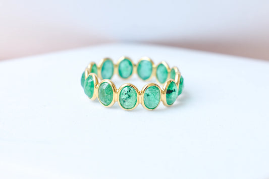Oval-cut emerald scalloped eternity ring in 18K gold