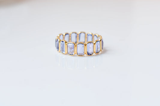 Emerald-cut tanzanite single-row eternity ring in 18K gold
