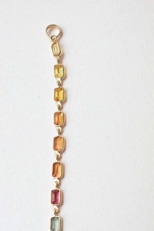 18K gold pendant with a graduated line of bezel-set multicolor sapphires
