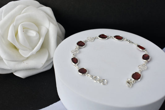 Garnet station bracelet with bezel-set stones and filigree flower links in 925 silver