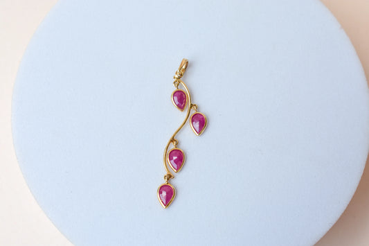 18K gold pendant with four bezel-set pear rubies on a vine design