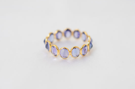 Oval-cut tanzanite gemstone eternity ring in 18K gold with bezel setting