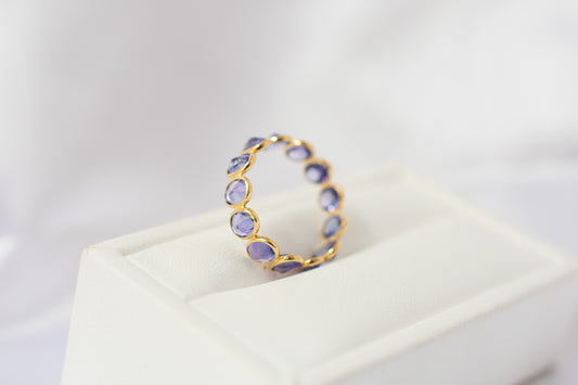 Oval-cut tanzanite gemstone eternity ring in 18K gold with bezel setting