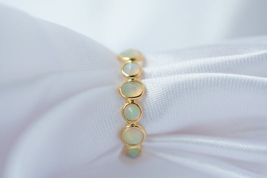 Cabochon opal gemstone eternity ring in 18K gold with bezel setting