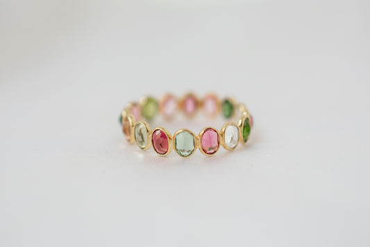 Oval-cut multicolor tourmaline gemstone eternity ring in 18K gold with bezel setting