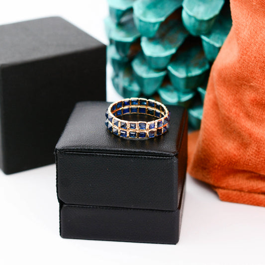 18K gold eternity ring with princess-cut blue sapphires in a channel-set grid