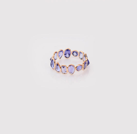 18K gold eternity ring with mixed-cut tanzanite stones in a mosaic pattern
