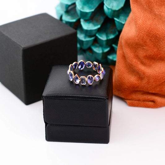 18K gold eternity ring with mixed-cut tanzanite stones in a mosaic pattern
