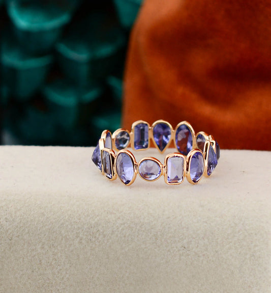 18K gold eternity ring with mixed-cut tanzanite stones in a mosaic pattern