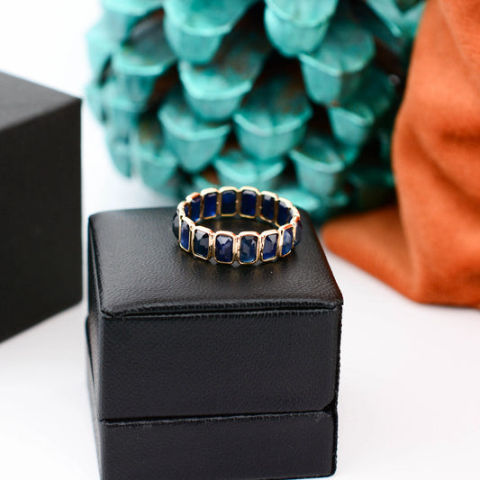 18K gold eternity ring with bezel-set emerald-cut blue sapphires