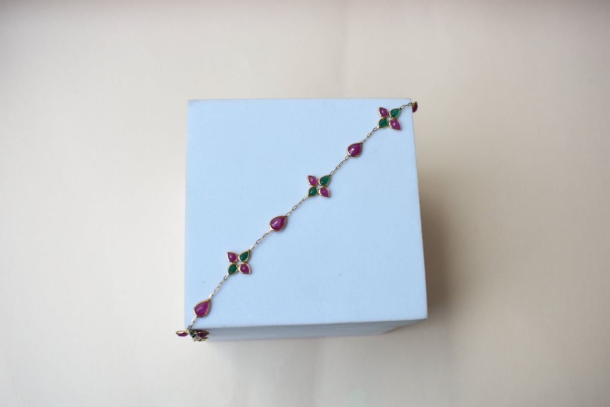 Gold bracelet with ruby and emerald quatrefoil clusters
