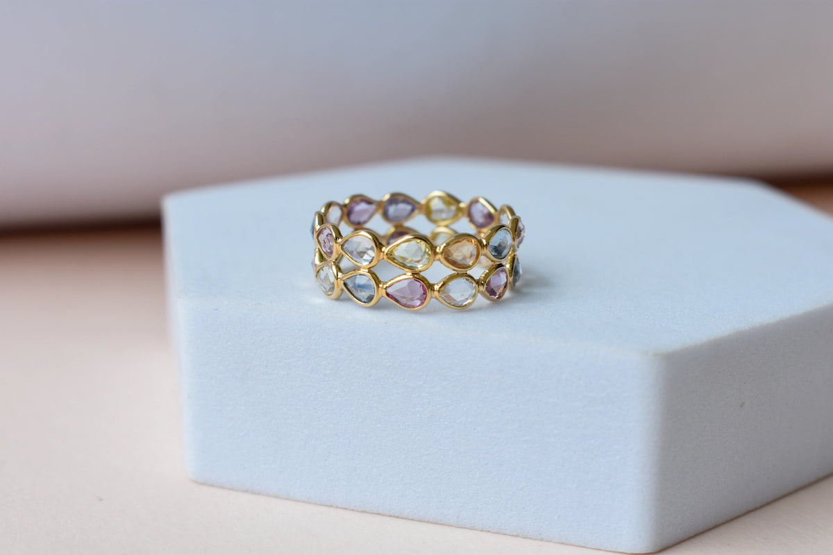 Pear-cut pastel multicolor sapphire eternity ring in 18K gold
