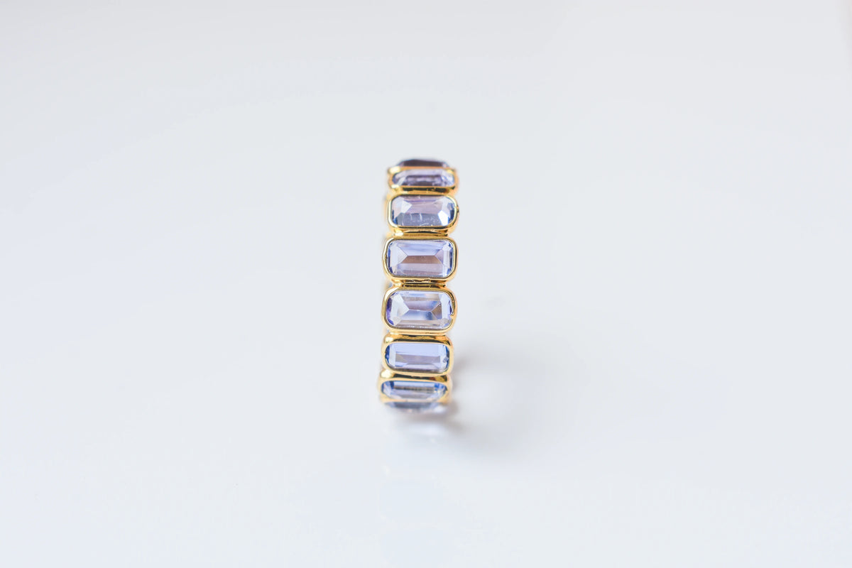 Emerald-cut tanzanite single-row eternity ring in 18K gold