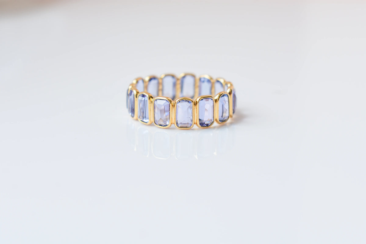 Emerald-cut tanzanite single-row eternity ring in 18K gold