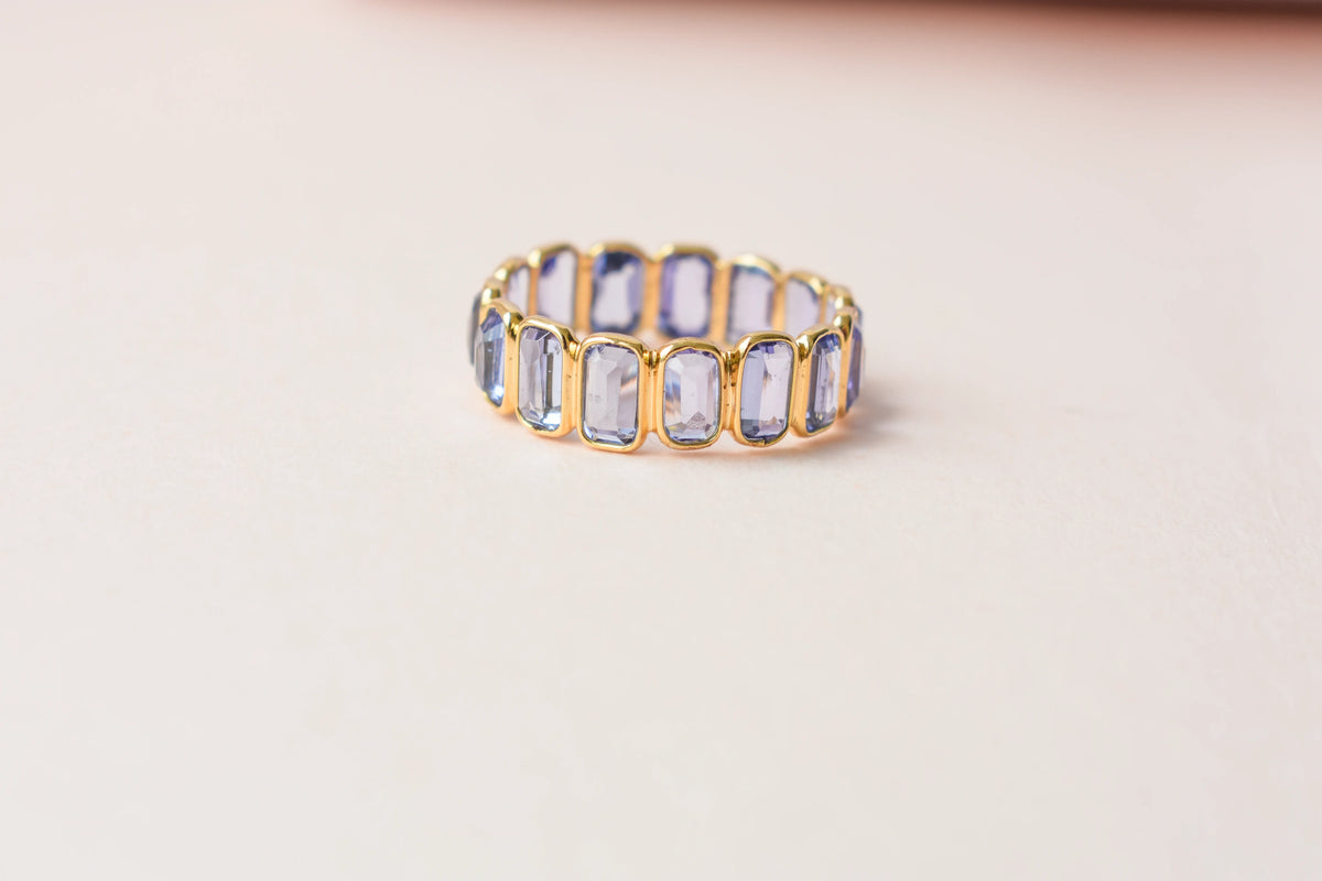 Emerald-cut tanzanite single-row eternity ring in 18K gold