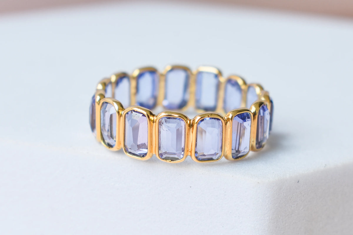 Emerald-cut tanzanite single-row eternity ring in 18K gold