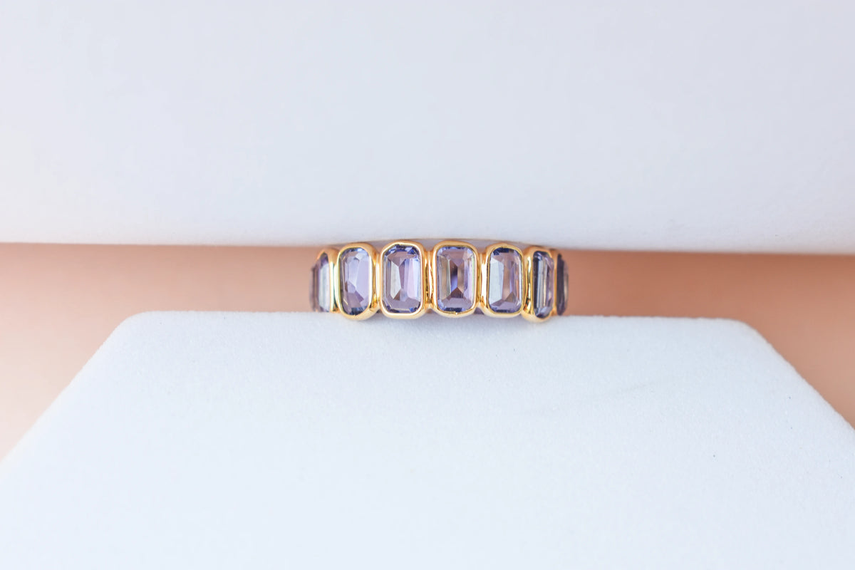 Emerald-cut tanzanite single-row eternity ring in 18K gold