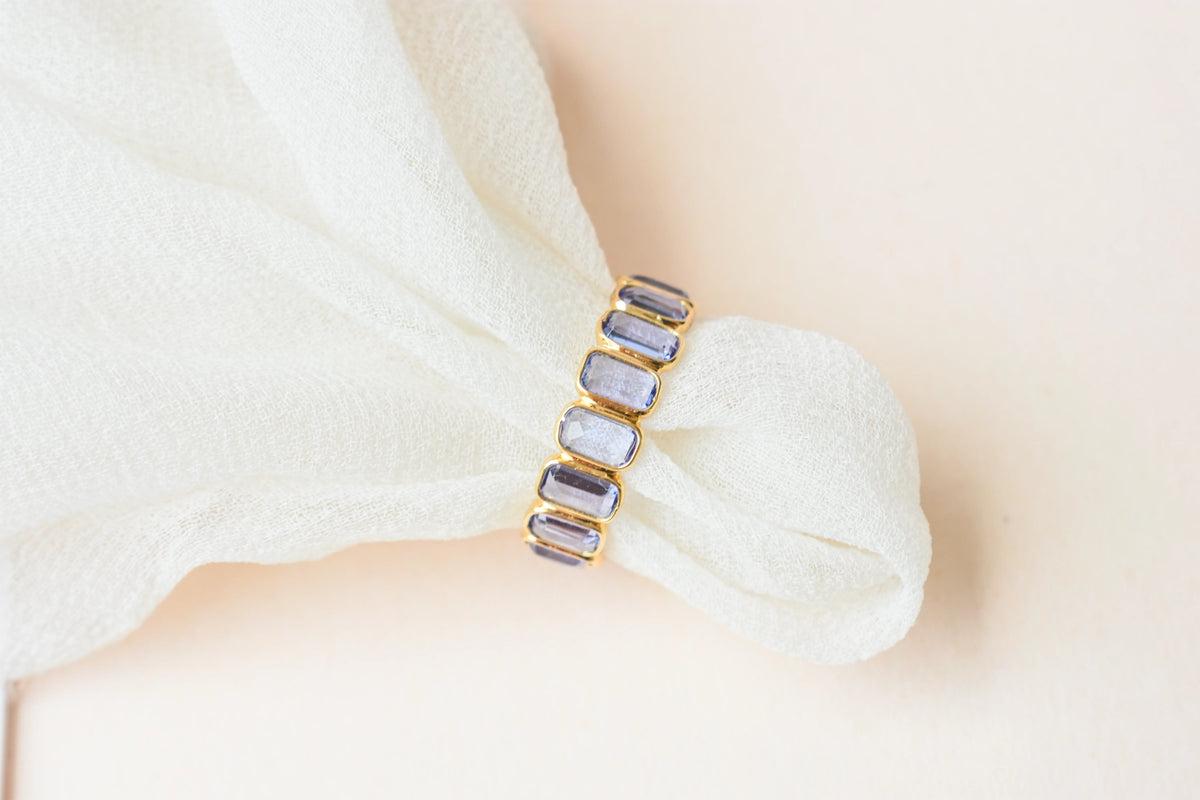 Emerald-cut tanzanite single-row eternity ring in 18K gold