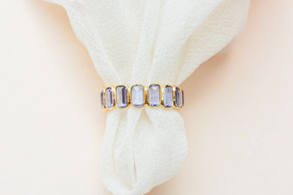 Emerald-cut tanzanite single-row eternity ring in 18K gold