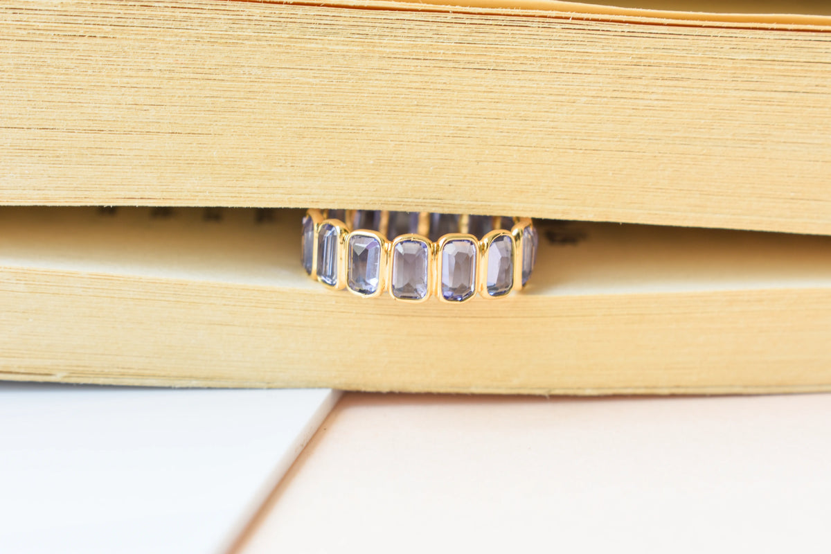 Emerald-cut tanzanite single-row eternity ring in 18K gold