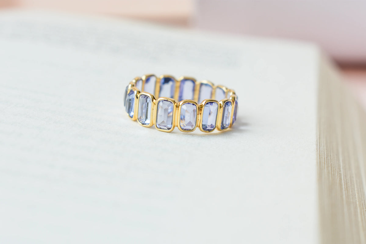 Emerald-cut tanzanite single-row eternity ring in 18K gold
