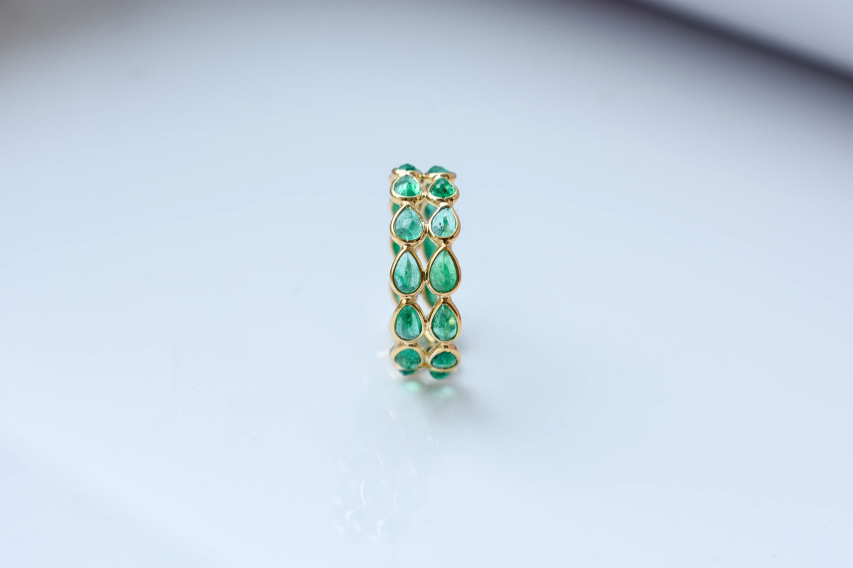 Pear-cut emerald lattice eternity ring in 18K gold with bezel setting
