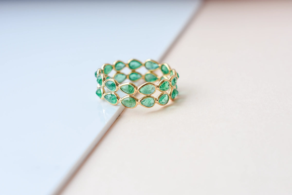 Pear-cut emerald lattice eternity ring in 18K gold with bezel setting