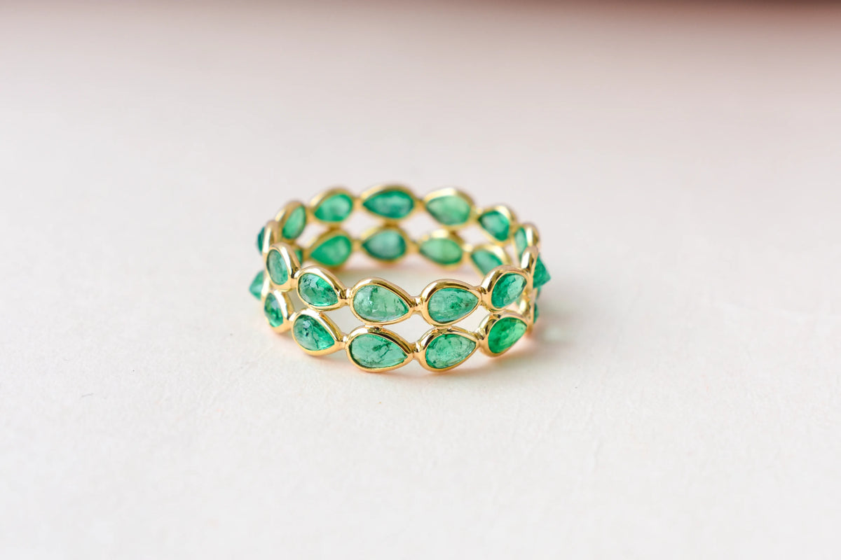 Pear-cut emerald lattice eternity ring in 18K gold with bezel setting
