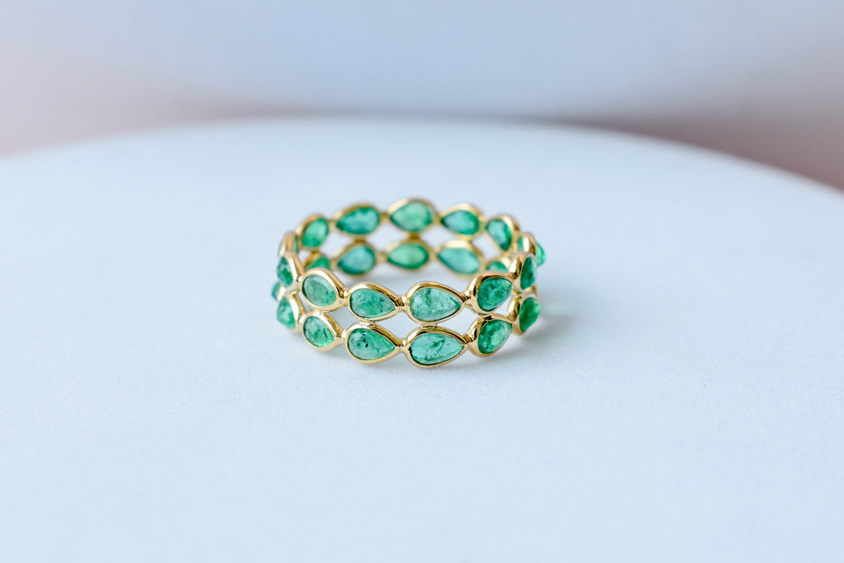 Pear-cut emerald lattice eternity ring in 18K gold with bezel setting