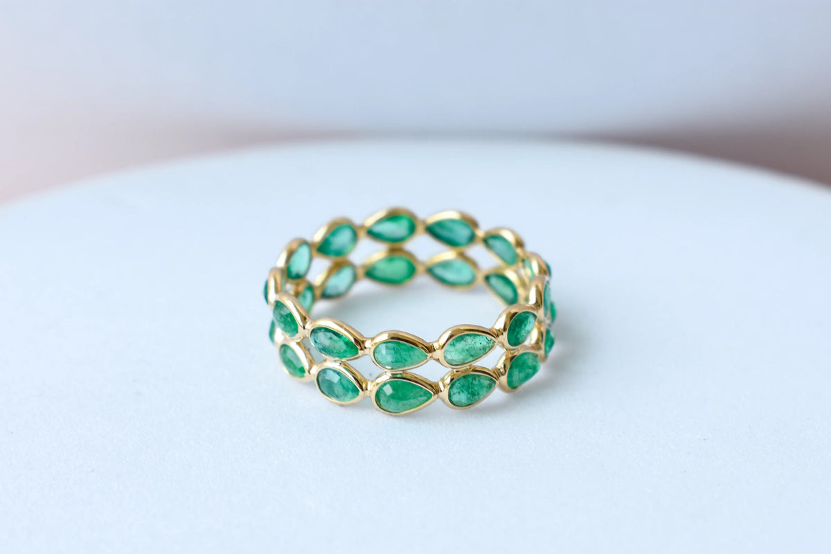Pear-cut emerald lattice eternity ring in 18K gold with bezel setting