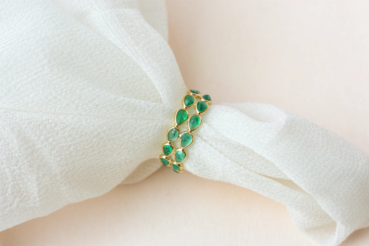 Pear-cut emerald lattice eternity ring in 18K gold with bezel setting