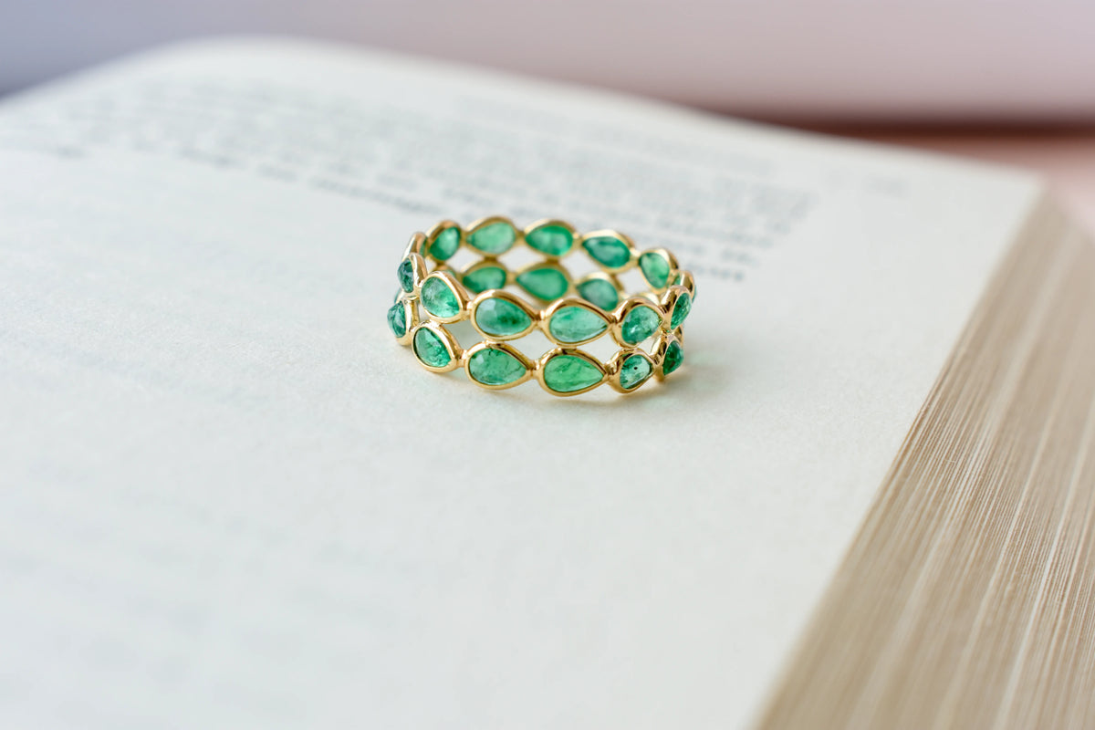Pear-cut emerald lattice eternity ring in 18K gold with bezel setting