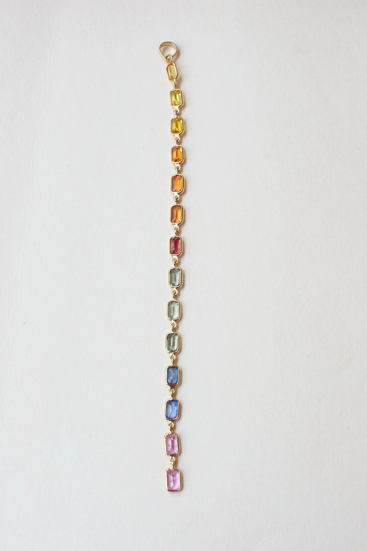 18K gold pendant with a graduated line of bezel-set multicolor sapphires