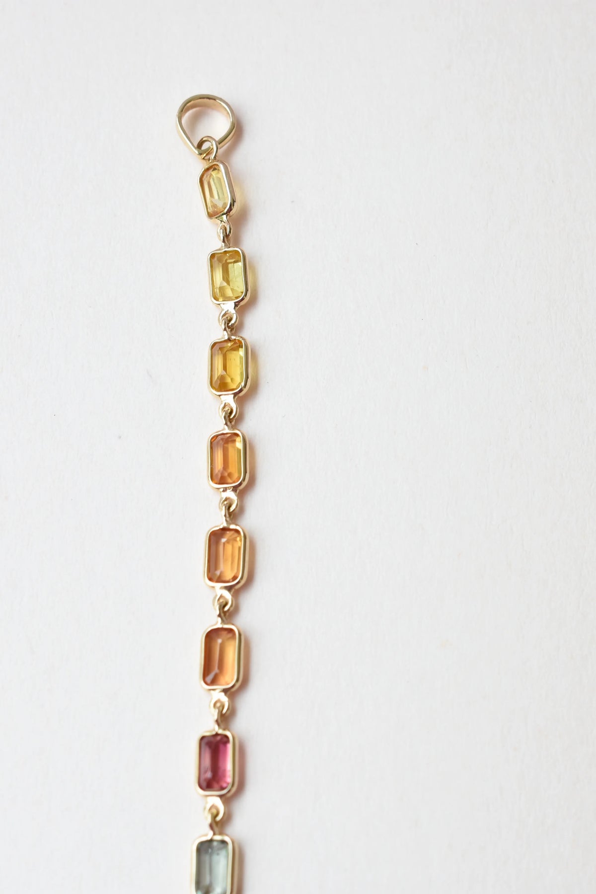 18K gold pendant with a graduated line of bezel-set multicolor sapphires