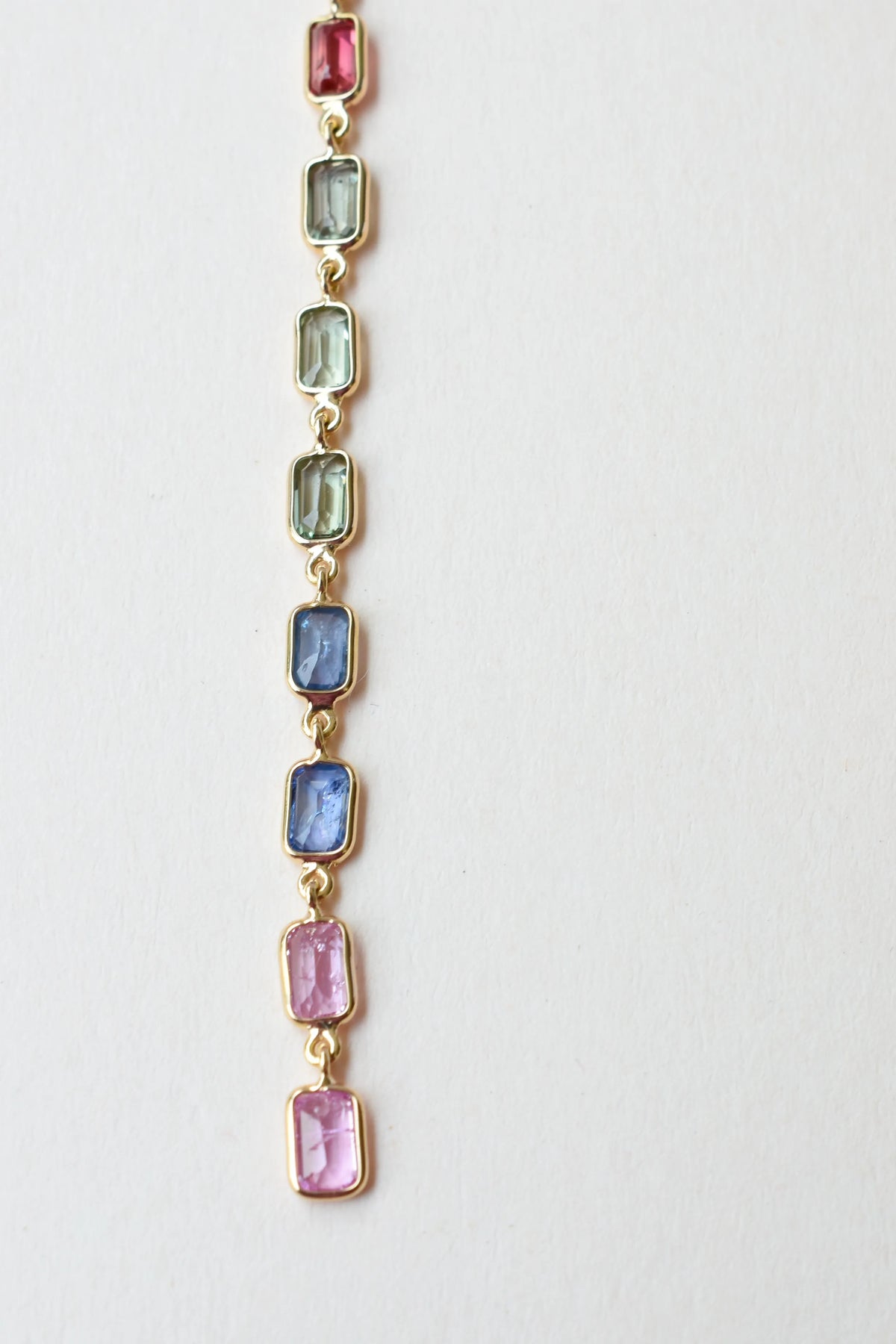 18K gold pendant with a graduated line of bezel-set multicolor sapphires