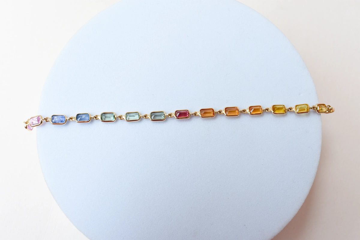 18K gold pendant with a graduated line of bezel-set multicolor sapphires