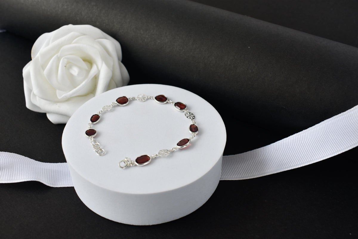 Garnet station bracelet with bezel-set stones and filigree flower links in 925 silver