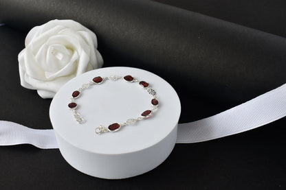 Garnet station bracelet with bezel-set stones and filigree flower links in 925 silver