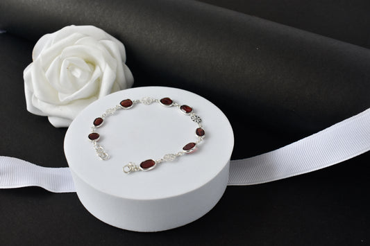 Garnet station bracelet with bezel-set stones and filigree flower links in 925 silver