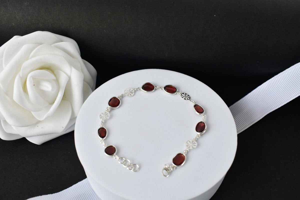 Garnet station bracelet with bezel-set stones and filigree flower links in 925 silver