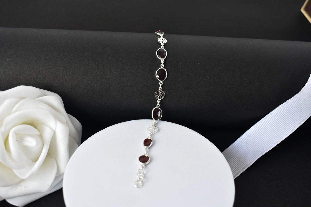 Garnet station bracelet with bezel-set stones and filigree flower links in 925 silver