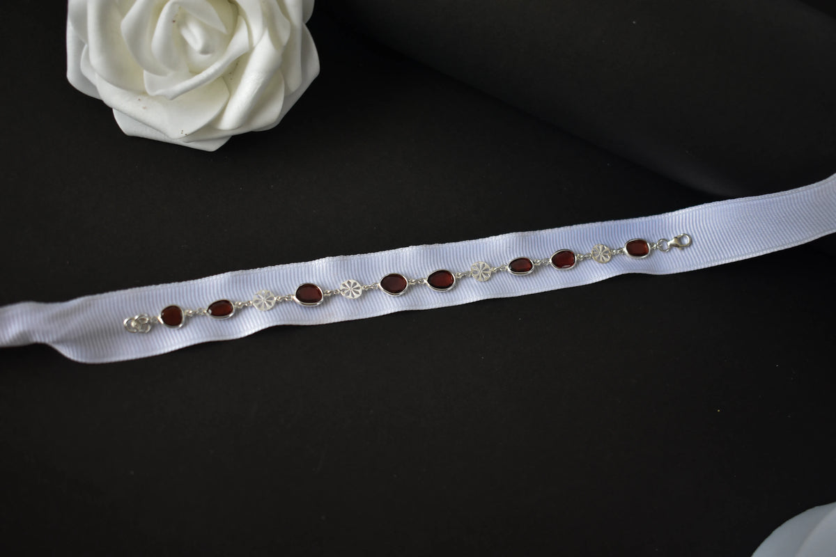 Garnet station bracelet with bezel-set stones and filigree flower links in 925 silver
