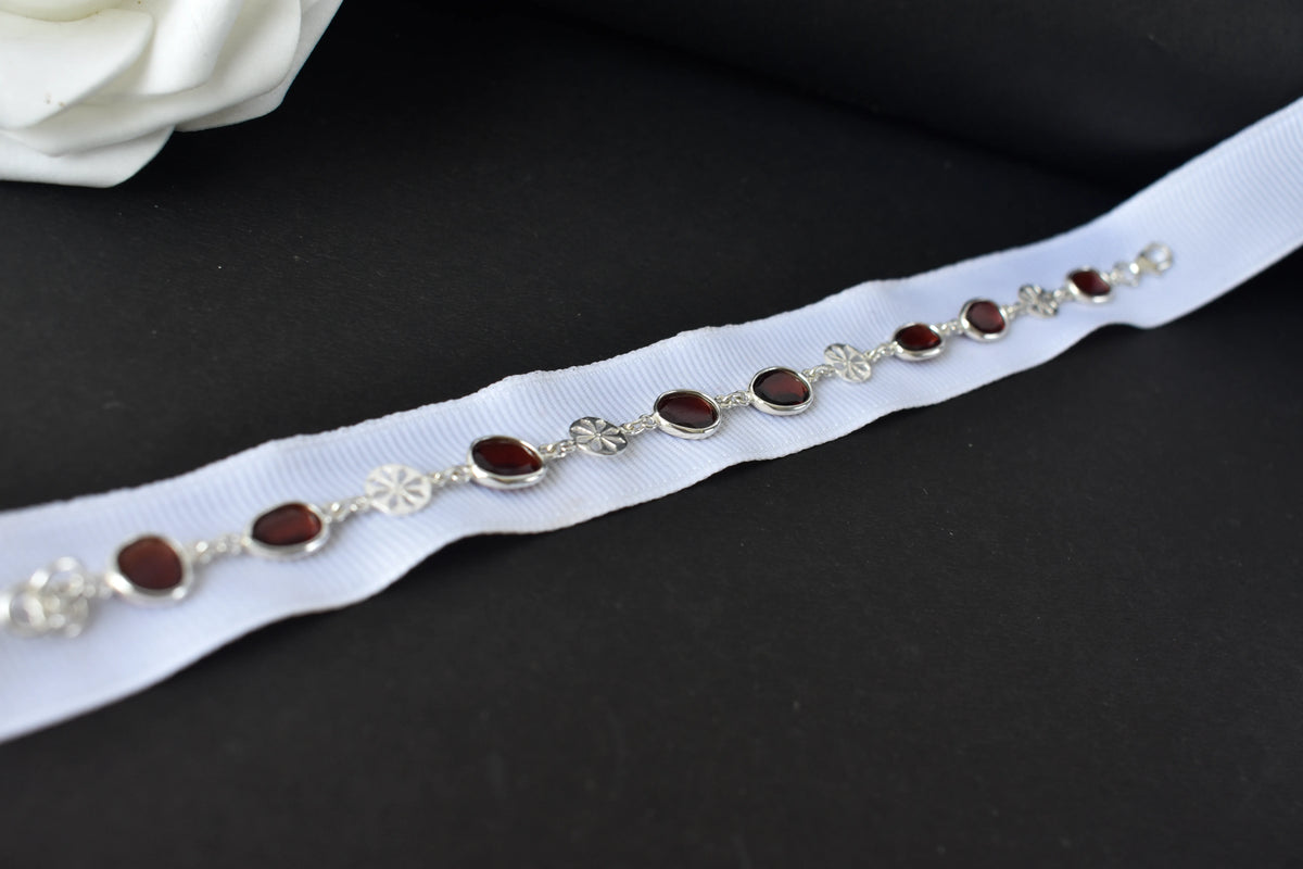 Garnet station bracelet with bezel-set stones and filigree flower links in 925 silver