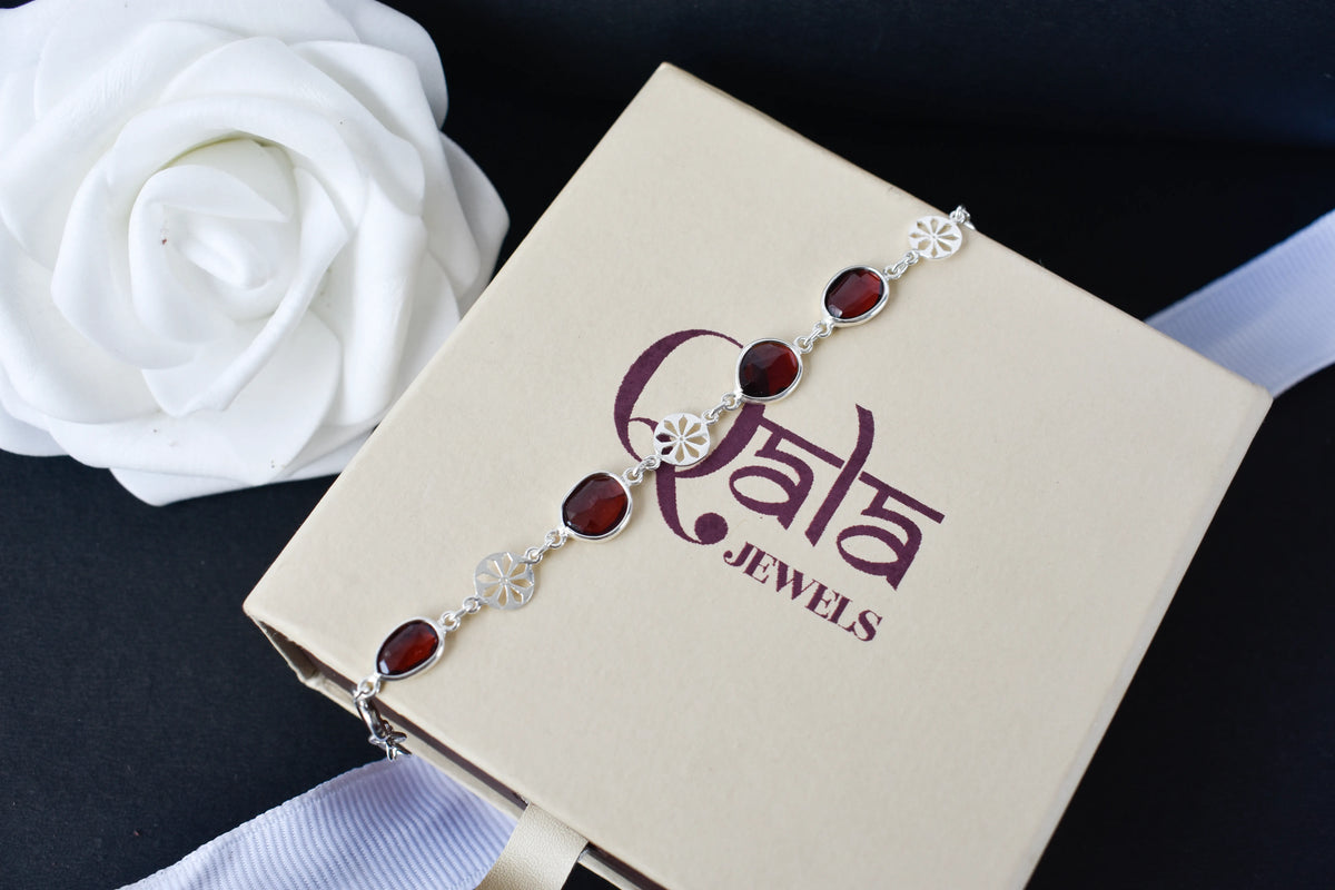 Garnet station bracelet with bezel-set stones and filigree flower links in 925 silver
