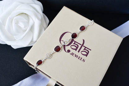 Garnet station bracelet with bezel-set stones and filigree flower links in 925 silver