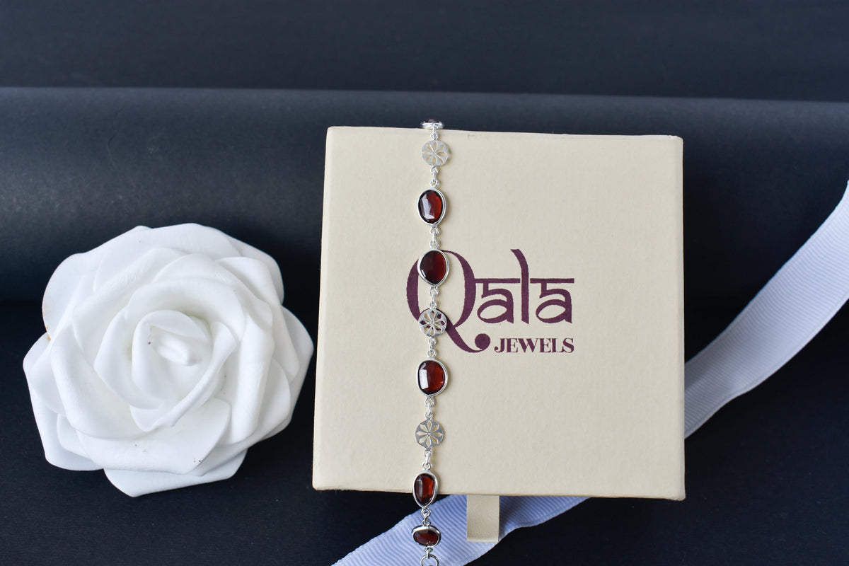 Garnet station bracelet with bezel-set stones and filigree flower links in 925 silver