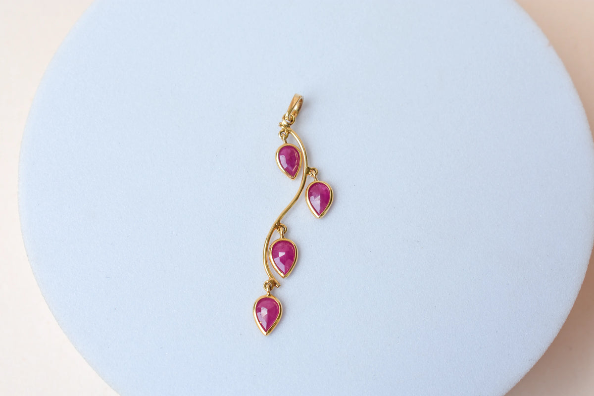 18K gold pendant with four bezel-set pear rubies on a vine design