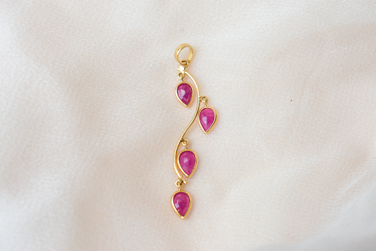 18K gold pendant with four bezel-set pear rubies on a vine design